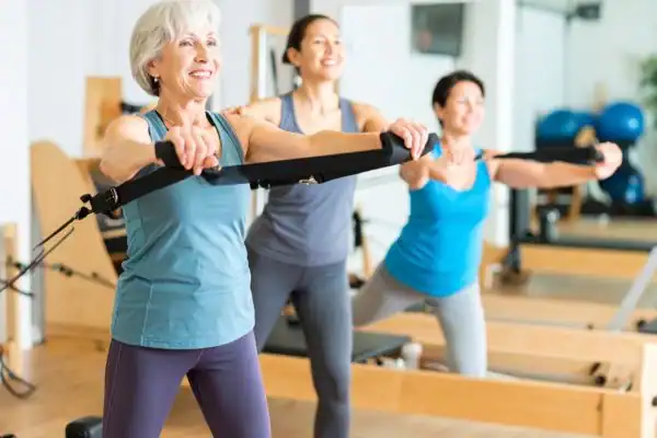 Toning Arms After 60: Empowering Womens Fitness Through Effective Weight Training 2 older woman doing weight training Bournemouth and resistance in the gym to tone upper arms
