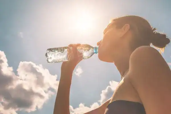 Hydration: The Secret Ingredient for a Toned Stomach and Enhanced Fitness 3 Image of woman drinking water to hydrate Bournemouth after run.